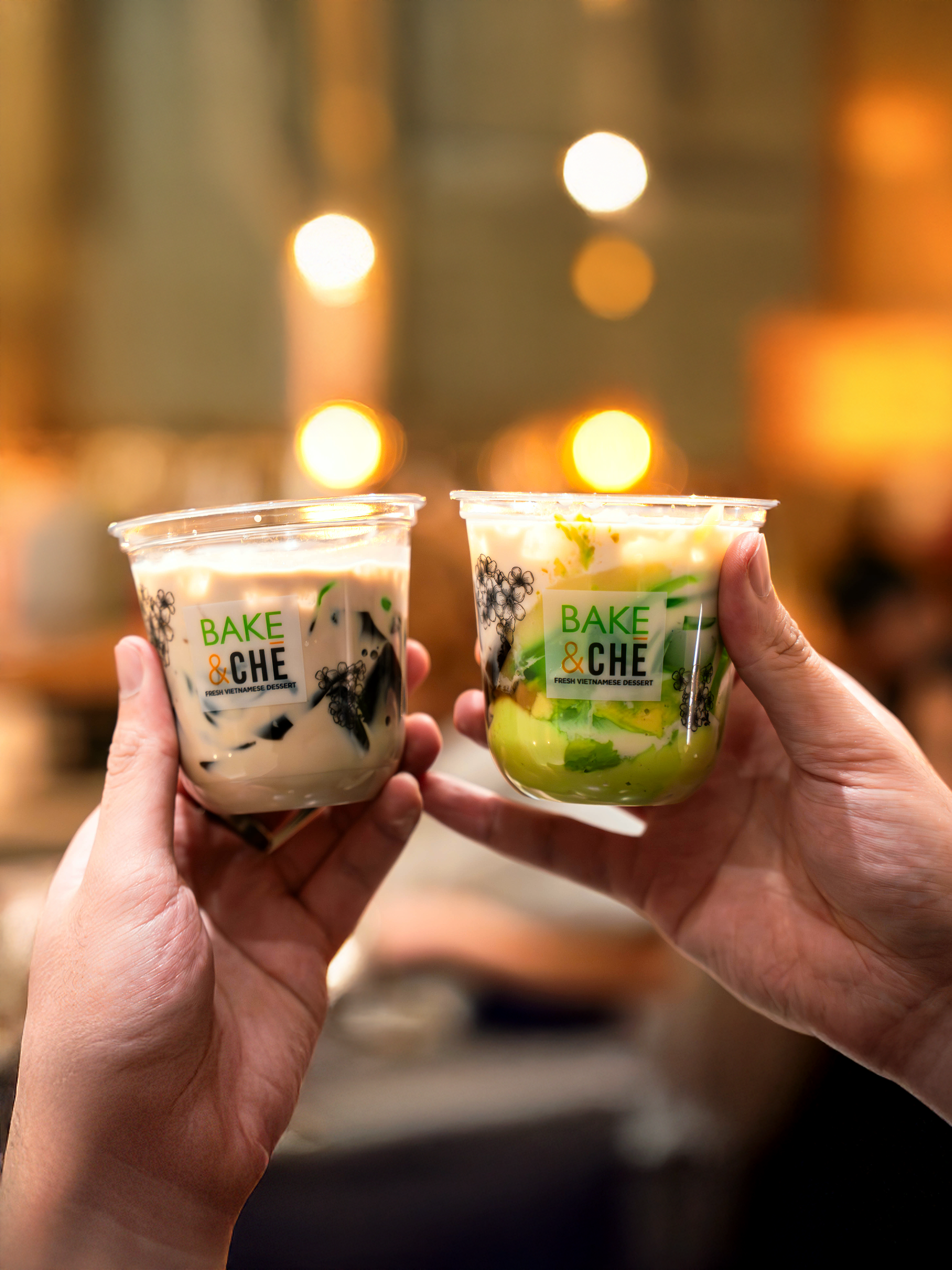 Two guests raising Bake & Che Vietnamese dessert cups in a cheers gesture